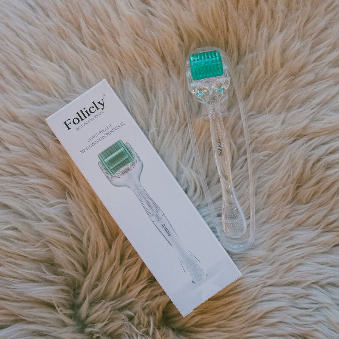 A Follierty dermal roller pen tool with a green roller head and clear handle, shown next to its white product box on a beige faux fur background.