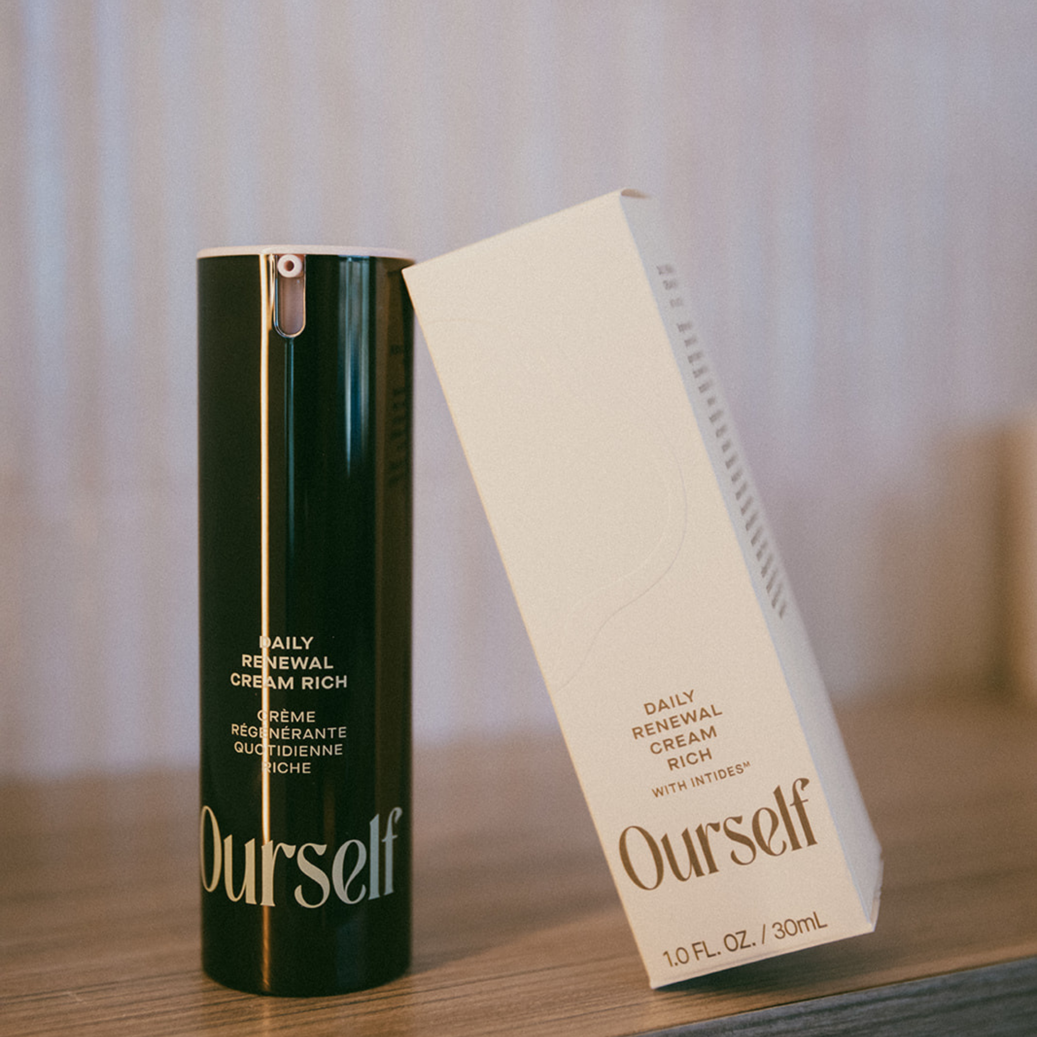 Skincare product and packaging labeled 'Ourself' on a wooden surface with a neutral background