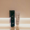 ZO Skin Health Hydrating Creme shown in a white squeeze tube next to its dark teal-blue packaging box, set against a warm beige background with a glowing horizontal light strip.